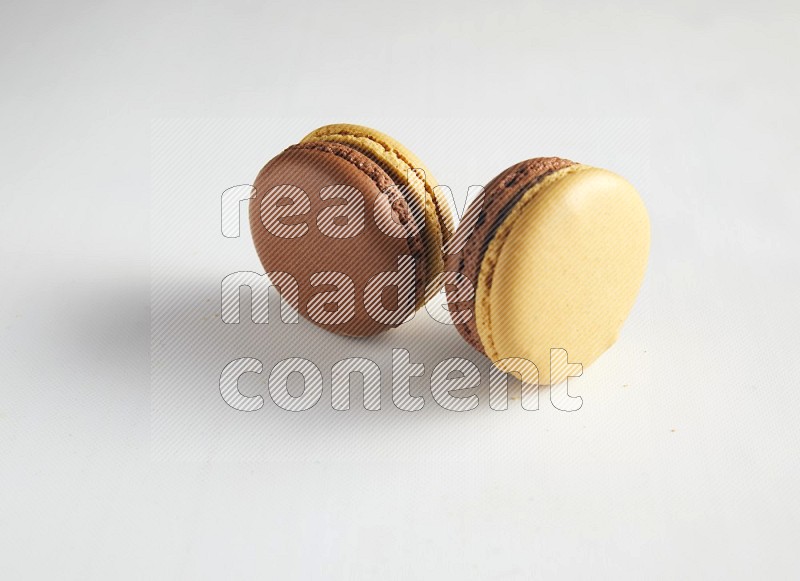 45º Shot of two Yellow and Brown Chai Latte macarons on white background