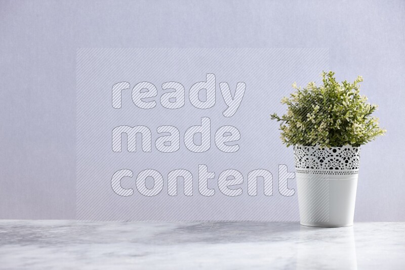 Artificial plant in white decorative pot on grey marble background