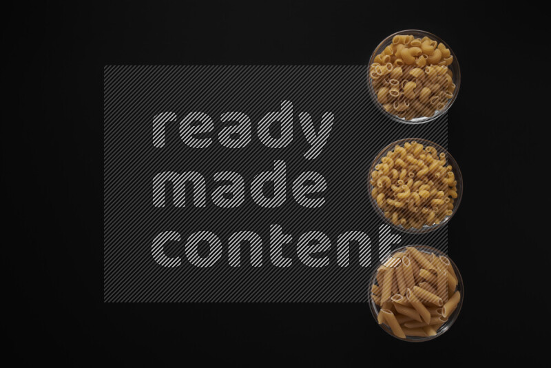 Different pasta types in 3 glass bowls on black background