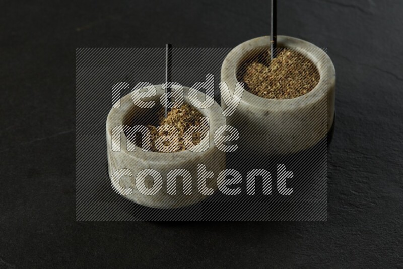 black and white round marble containers filled with herbs on gray textured countertop