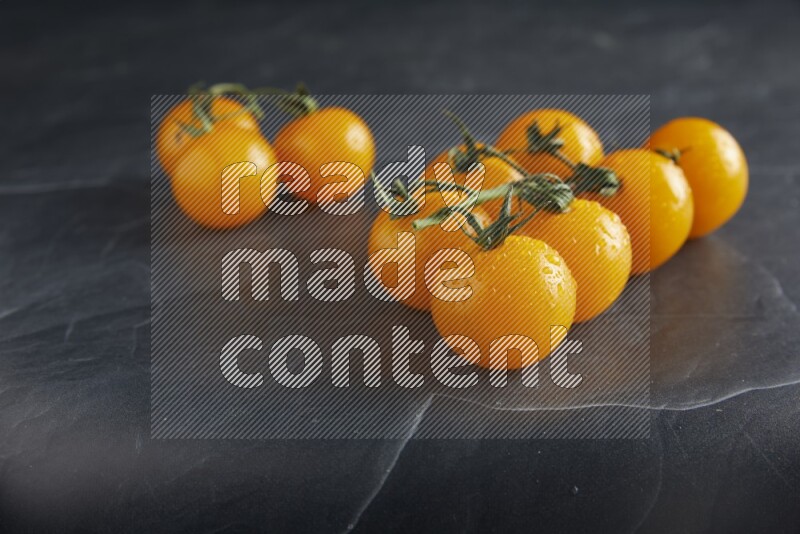 Yellow cherry tomato vein on a textured black slate background 45 degree