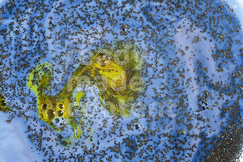 A close-up of sparkling gold glitter scattered on swirling blue and green background