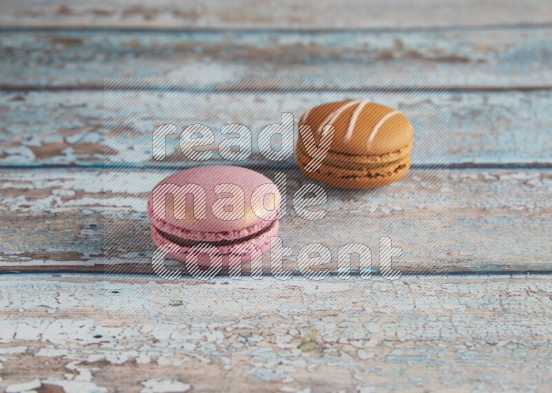 45º Shot of of two assorted Brown Irish Cream, and Purple Strawberry macarons  on light blue background