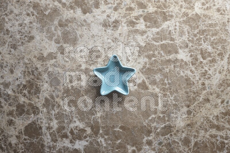 A colored pottery star plate on beige marble background