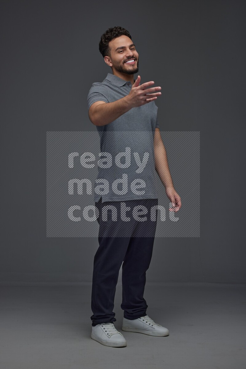 A man wearing casual standing and making multi hand gestures eye level on a gray background