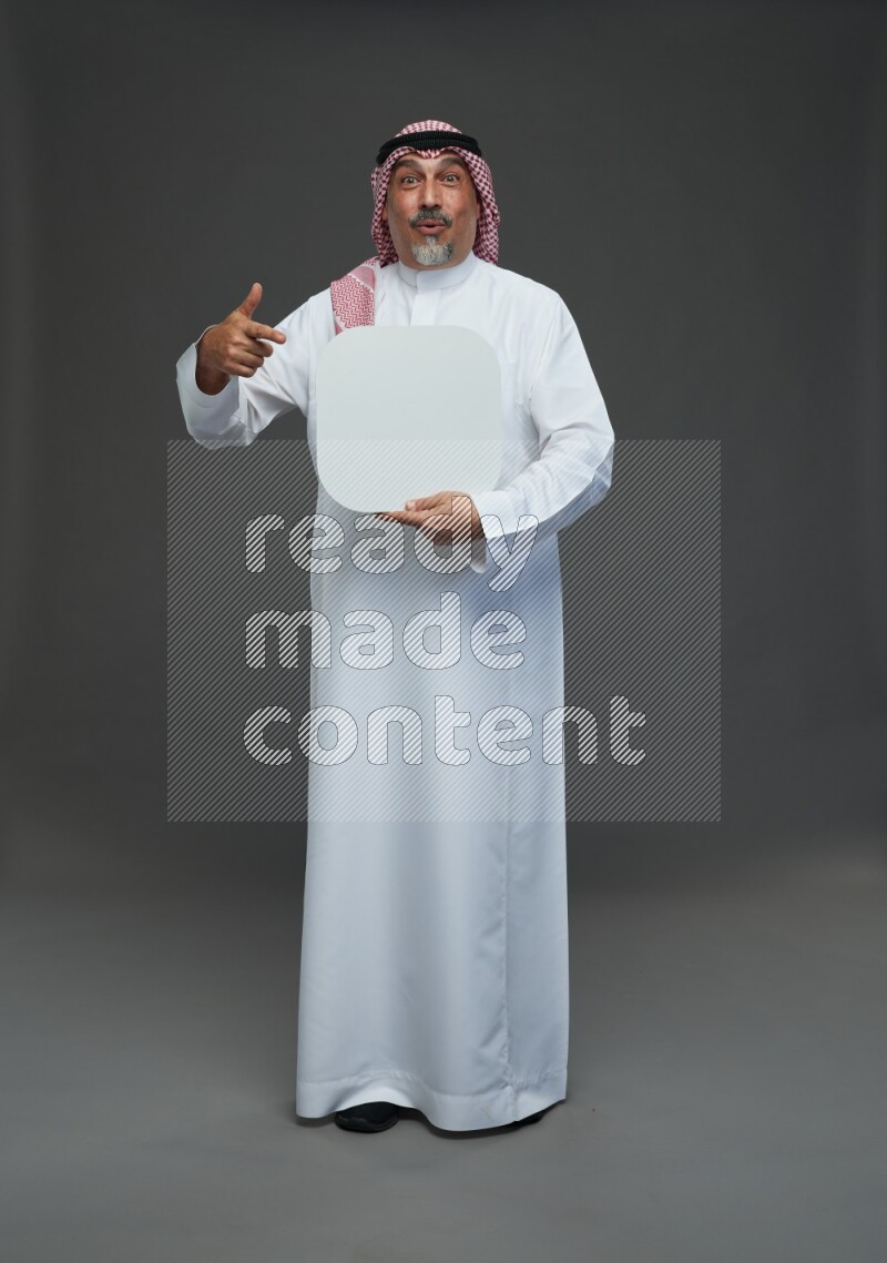 Saudi man with shomag Standing holding social media sing on gray background
