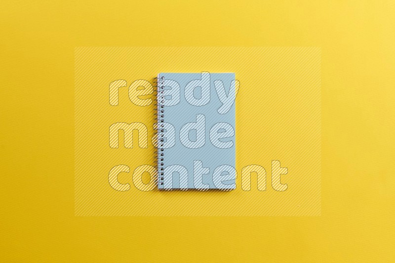 A blue notebook on yellow background (Back to school)