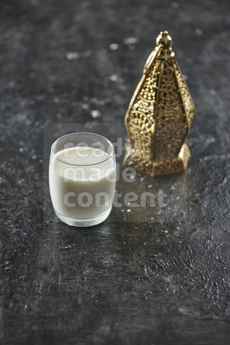 A golden lantern with different drinks, dates, nuts, prayer beads and quran on textured black background
