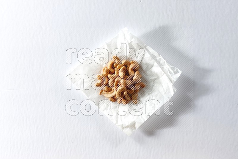 Cashews on a crumpled piece of paper on a white background in different angles