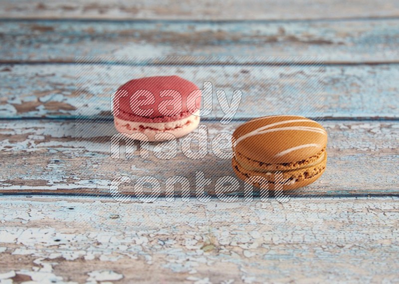 45º Shot of of two assorted Brown Irish Cream, and Pink Litchi Raspberry macarons on light blue background