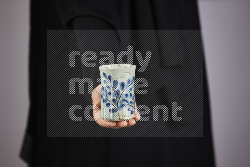 A woman in black abaya holding different pottery essentials in different positions