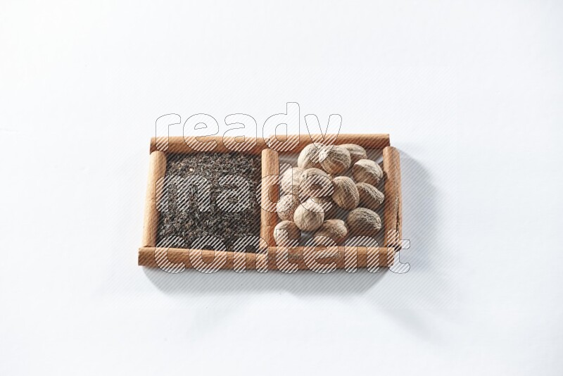 مربعان من أعواد القرفة ممتلئان بالشاي الأسود وجوزة الطيب علي خلفية بيضاء