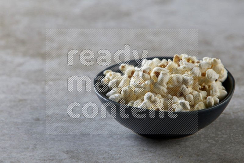 popcorn in black bowl on a grey textured countertop