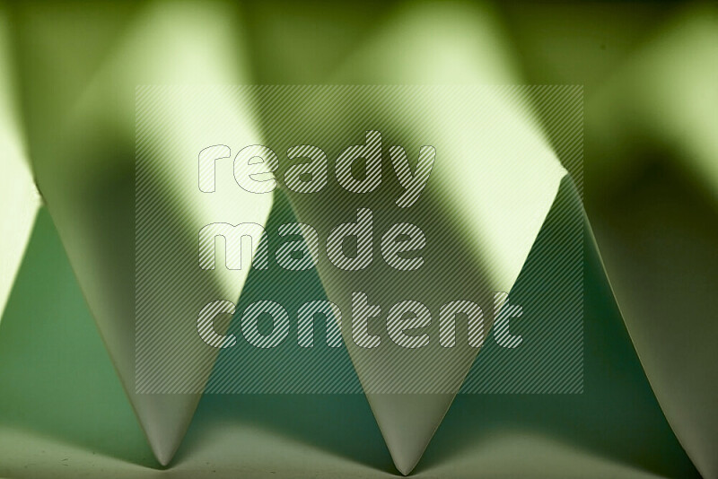 A close-up abstract image showing sharp geometric paper folds in green gradients
