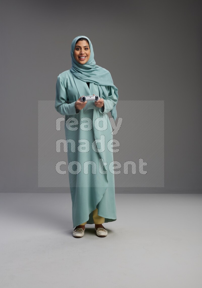 Saudi Woman wearing Abaya standing Playing Games on Gray background