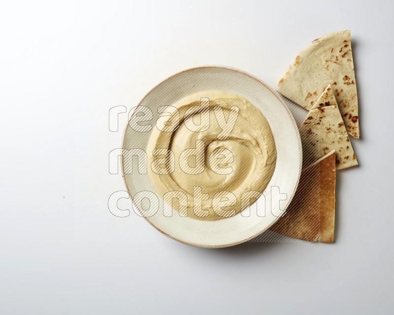 plain Hummus in a pottry plate  on a white background