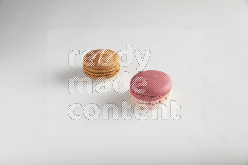 45º Shot of of two assorted Brown Irish Cream, and Pink Litchi Raspberry macarons on white background