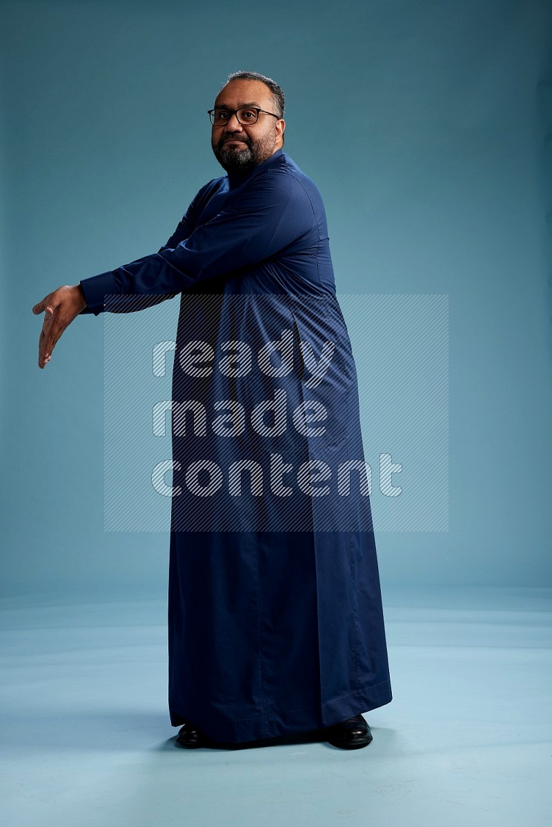 Saudi Man without shimag Standing Interacting with the camera on blue background