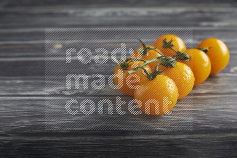 Yellow cherry tomato vein on a textured grey wooden background 45 degree