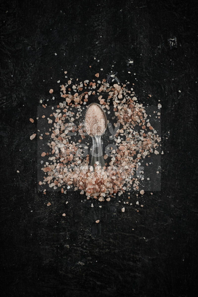 ملعقتان معدنيتان ممتلئتان بملح الهيمالايا الوردي على خلفية سوداء