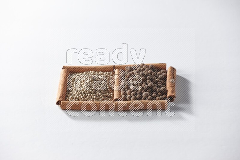 2 squares of cinnamon sticks full of white pepper and allspice on white flooring