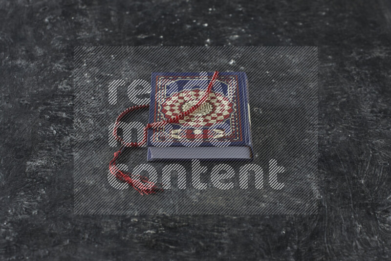 Quran with a prayer beads on textured black background