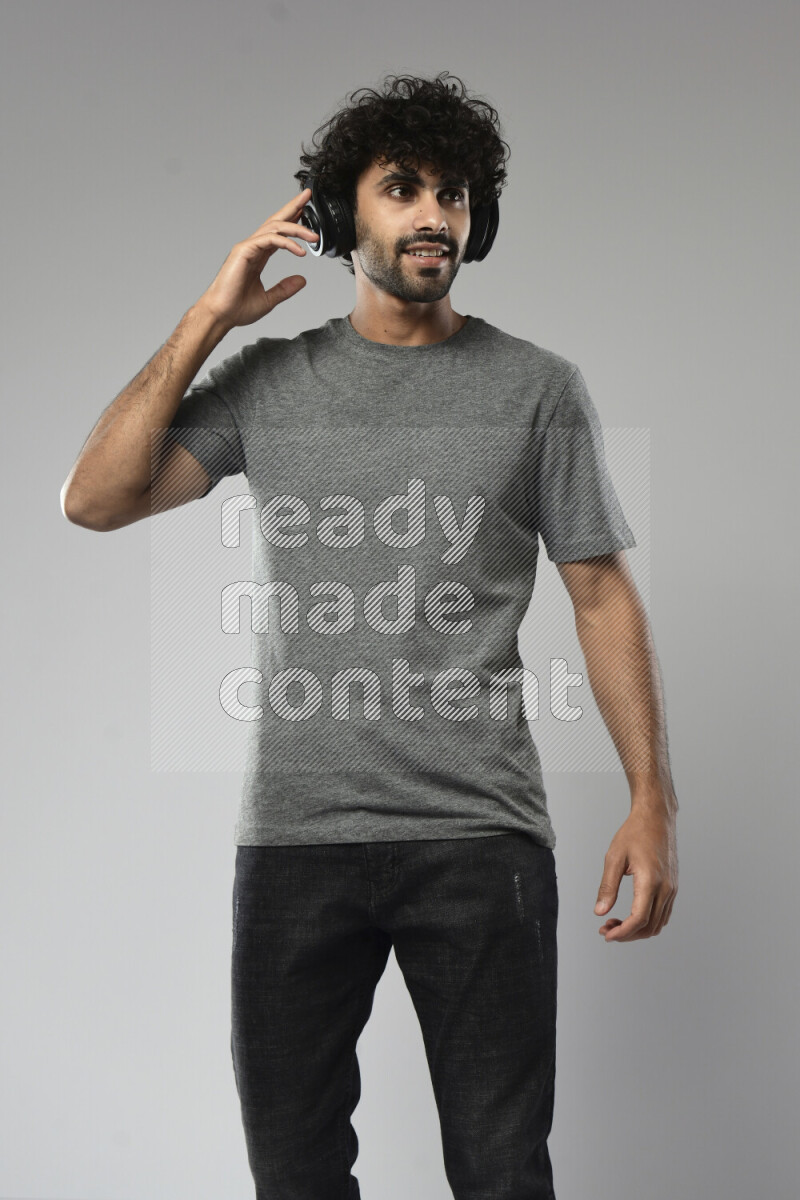 رجل يرتدي ملابس كاجوال يضع سماعات رأس علي خلفية بيضاء