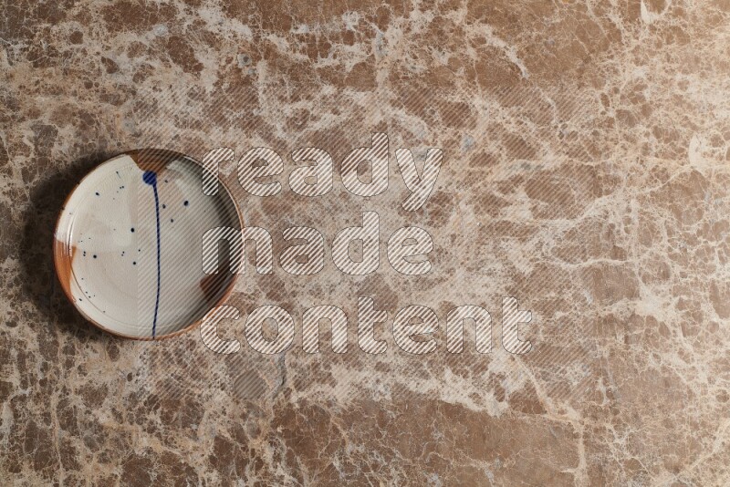 A multicolored pottery plate on beige marble background