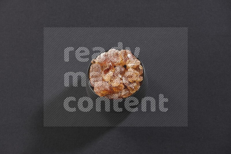 وعاء فخاري أسود ممتلئ بقطع الصمغ العربي علي خلفية سوداء