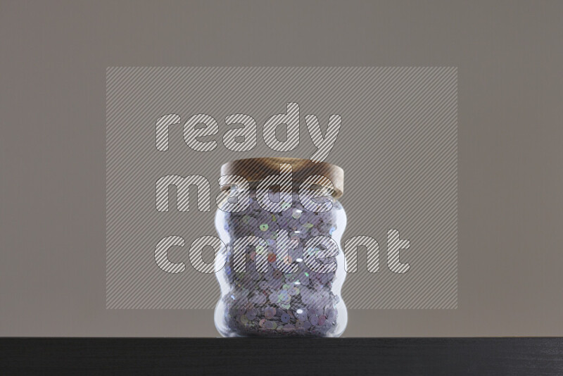 Sequins in a glass jar on black background