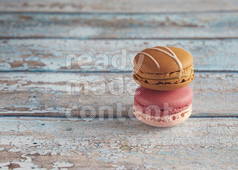 45º Shot of of two assorted Brown Irish Cream, and Pink Litchi Raspberry macarons on light blue background