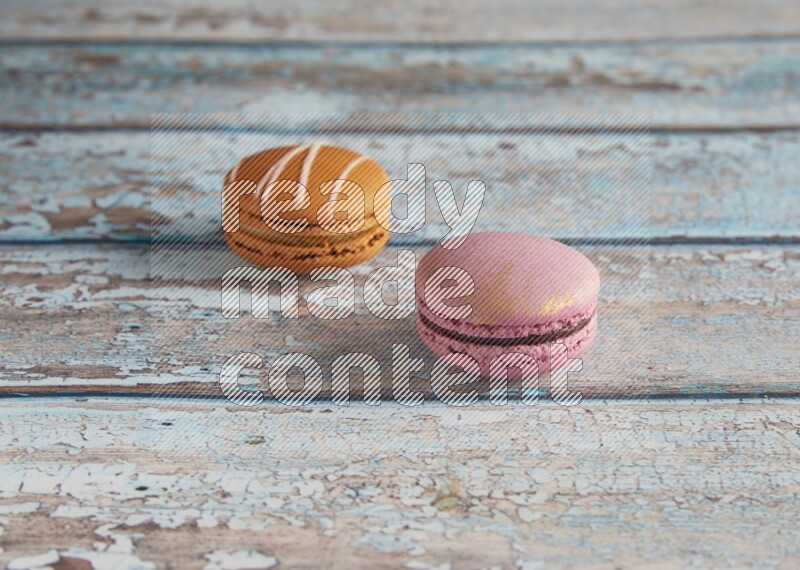 45º Shot of of two assorted Brown Irish Cream, and Purple Strawberry macarons  on light blue background