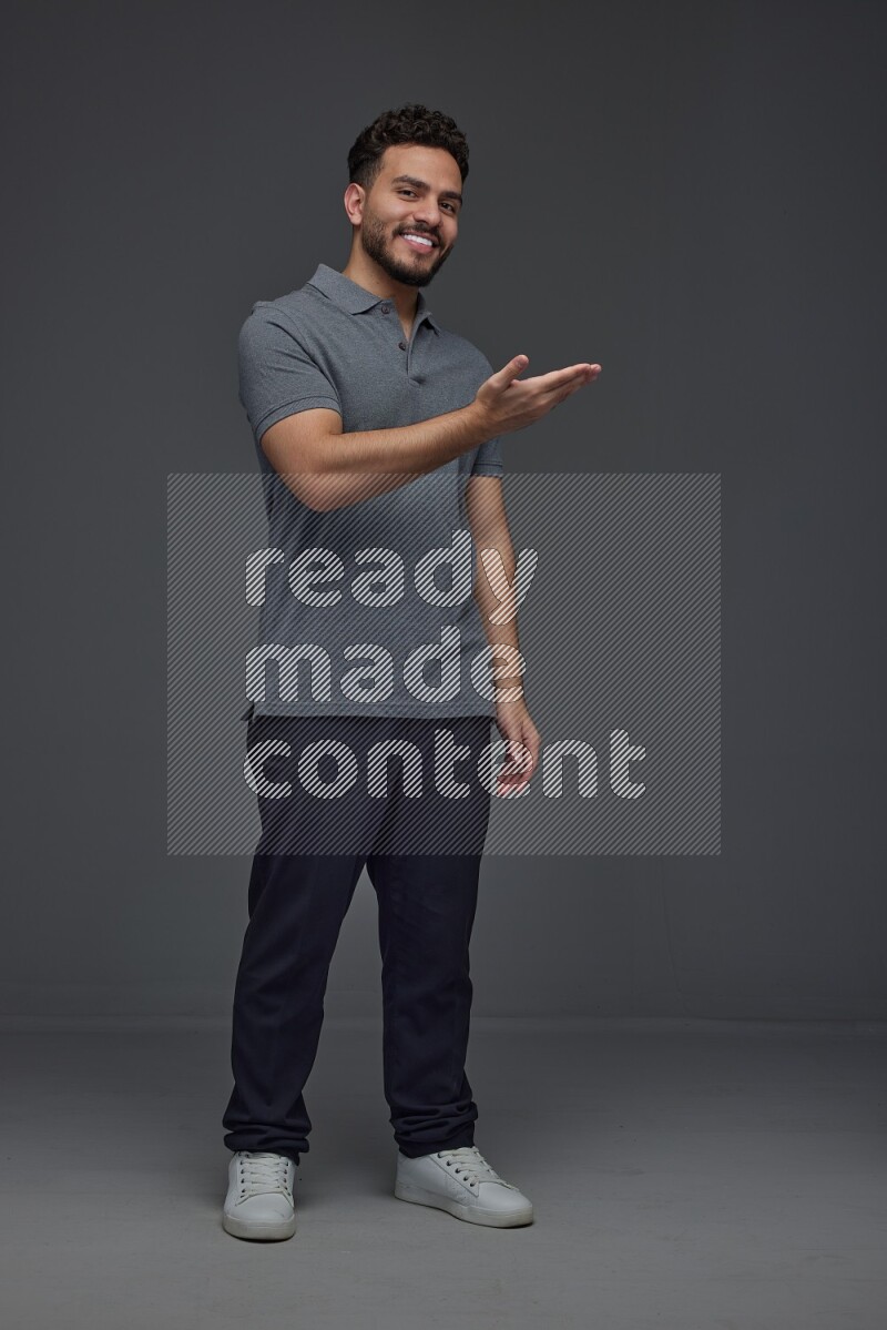 A man wearing casual standing and making multi hand gestures eye level on a gray background