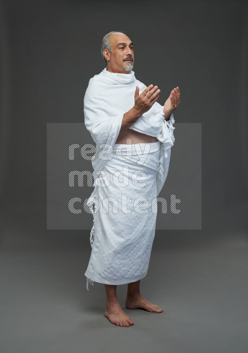 A man wearing Ehram Standing dua'a on gray background
