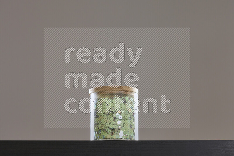 Sequins in a glass jar on black background