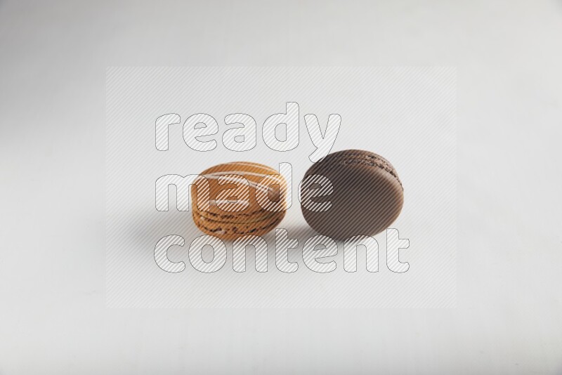 45º Shot of of two assorted Brown Irish Cream, and Brown Dark Chocolate macarons on white background
