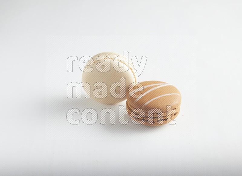 45º Shot of of two assorted Brown Irish Cream, and White Caramel fleur de sel macarons on white background