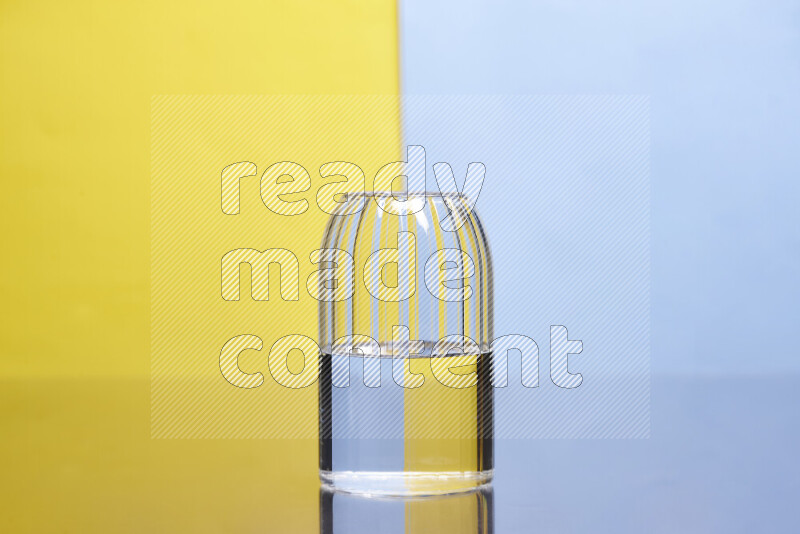 The image features a clear glassware filled with water, set against yellow and light blue background