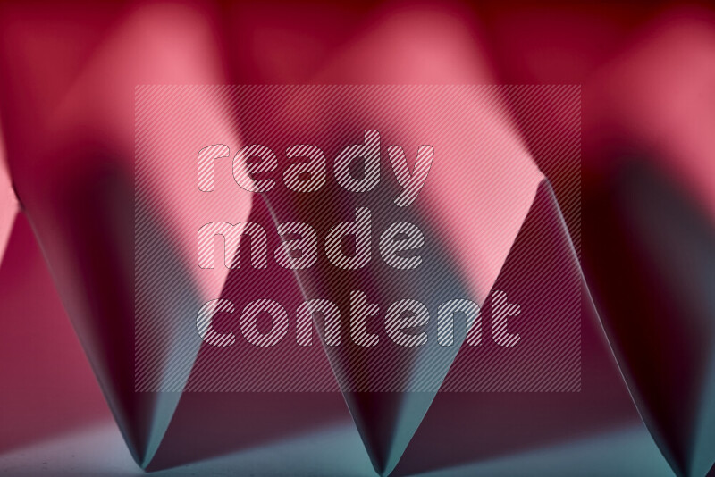A close-up abstract image showing sharp geometric paper folds in blue and red gradients