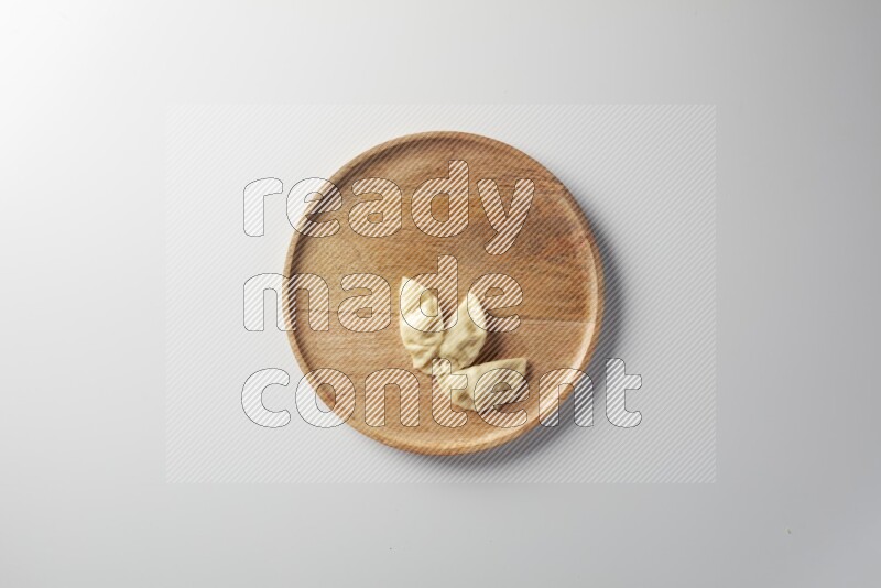 Three Sambosas on a wooden round plate on a white background