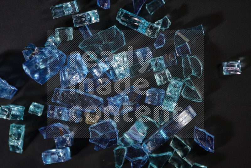 Transparent blue fragments of glass scattered on a black background