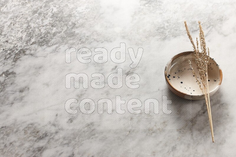 Wheat stalks on multicolored pottery bowl on grey marble background
