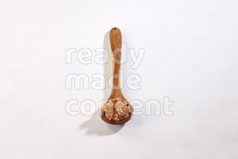 A wooden ladle filled with gum arabic on white flooring