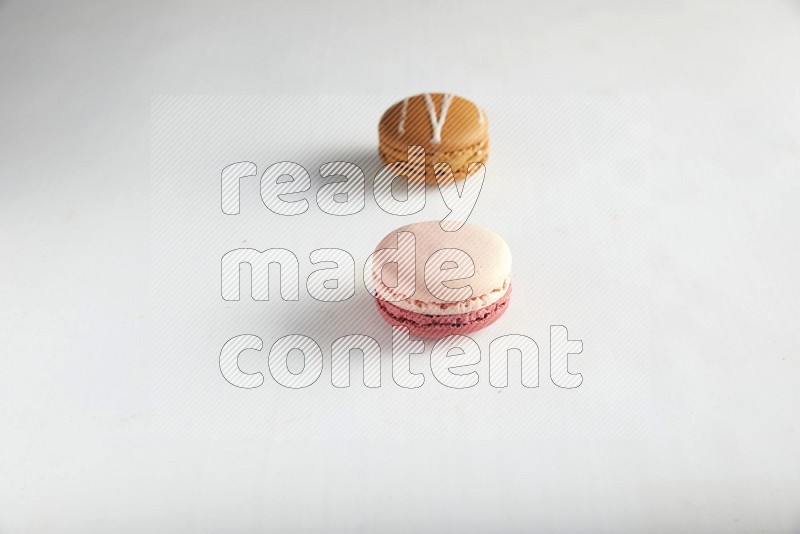 45º Shot of of two assorted Brown Irish Cream, and Pink Litchi Raspberry macarons on white background