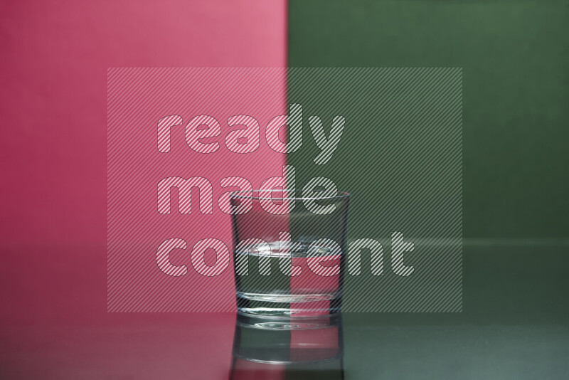 The image features a clear glassware filled with water, set against pink and dark green background