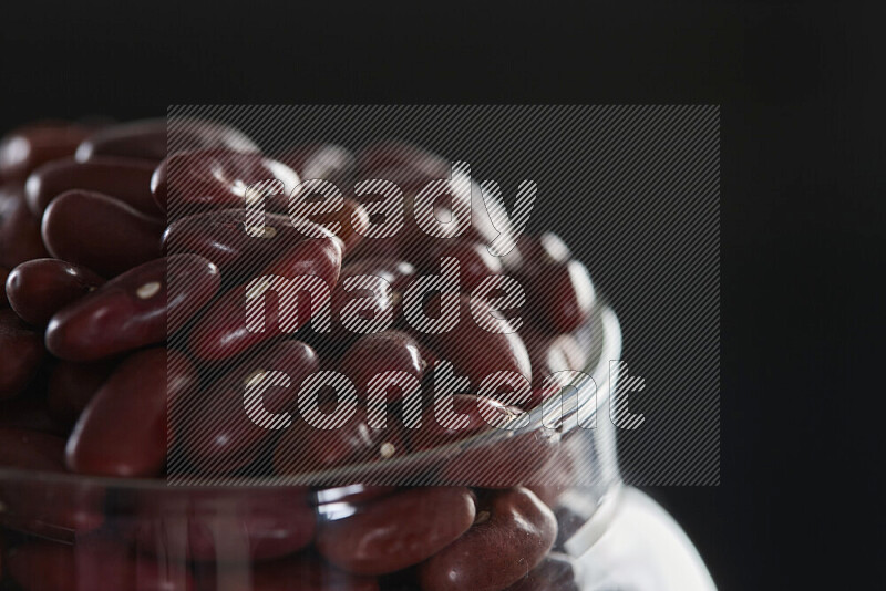 Red kidney beans in a glass jar on black background