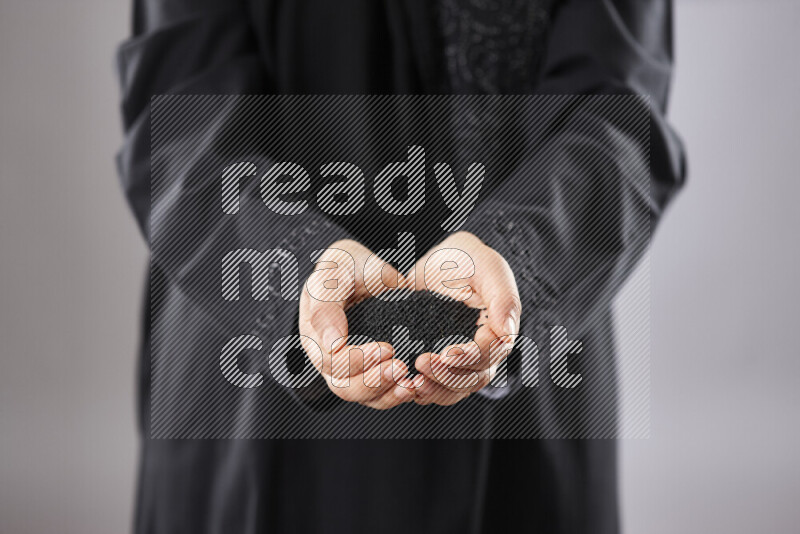 Woman in abaya holding different kinds of spices in different positions