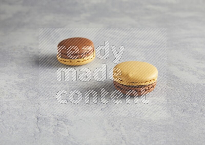 45º Shot of two Yellow and Brown Chai Latte macarons r on white  marble background