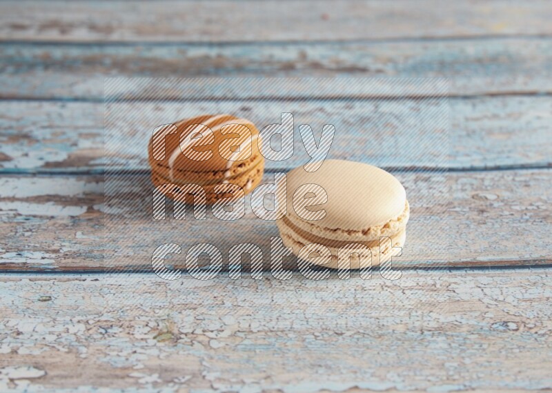 45º Shot of of two assorted Brown Irish Cream, and White Caramel fleur de sel macarons on light blue background