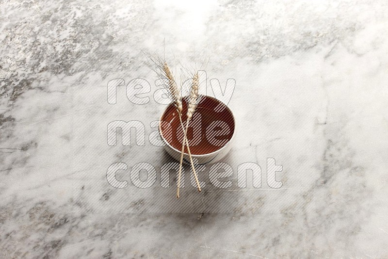 Wheat stalks on Brown Pottery Bowl on grey marble flooring, 45 degree angle